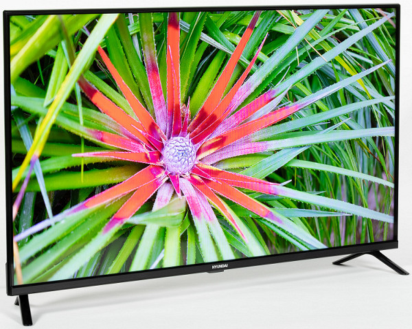 The TV's design is modest and modern, with a «bezel-less» style based on black or a similar color. The screen is frameless on three sides, having only a thin plastic bezel, and at the bottom of the frame there is a plastic insert with the brand logo in the center. The screen panel is slightly recessed into the body, creating a feeling of lightness and smoothness of the image, as if it were floating in the air.