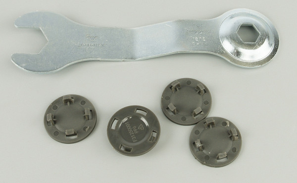 The metal key is used to adjust the height of the device's legs, and the plastic plugs are inserted into the holes left by the transport bolts.